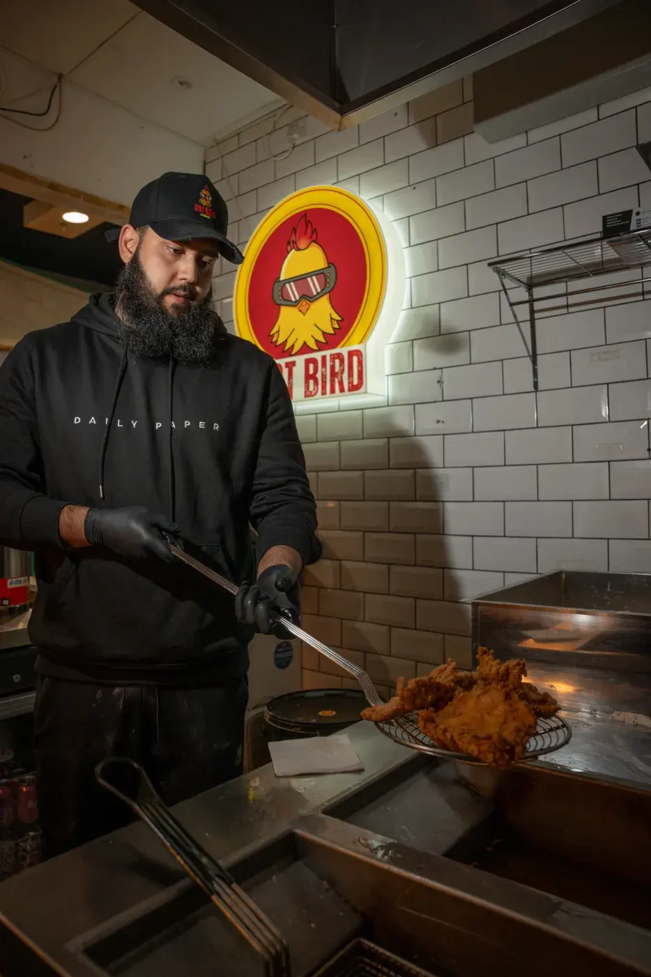 Chef at work with the Hot Bird neon sign behind